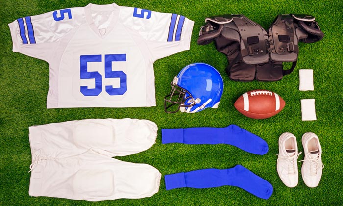 Football uniform, ball and helmet laying on grassy field
