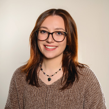 Audrey Emerson, in brown v-neck sweater with big smile.