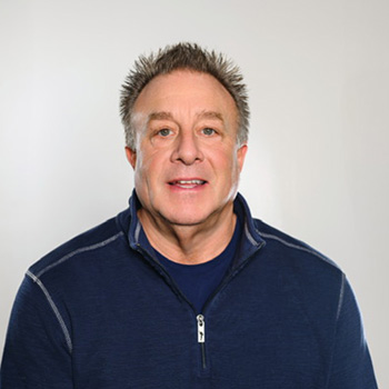 Todd Mellon in navy zip-jacket, smiling at camera.